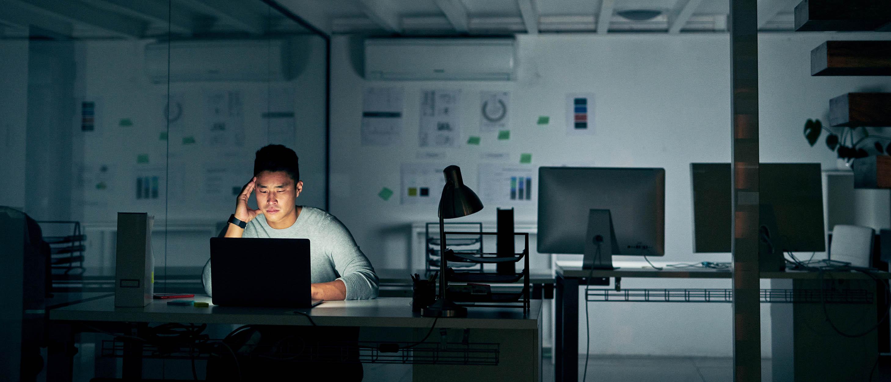 En person sitter ensamt på ett mörkt kontor