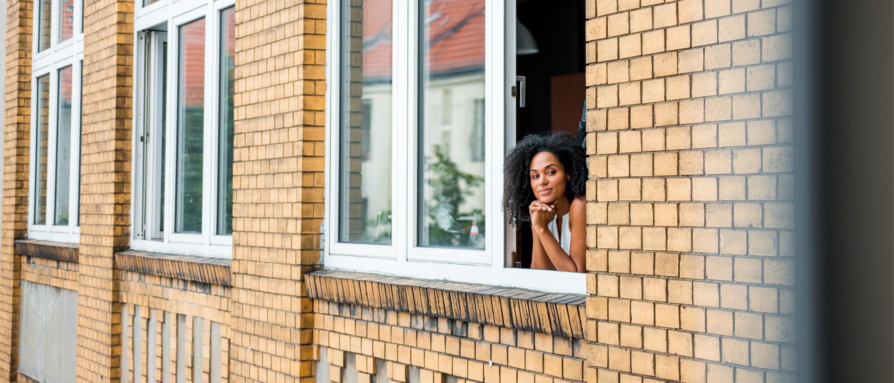 En kvinna står vid fönstret och tittar utåt
